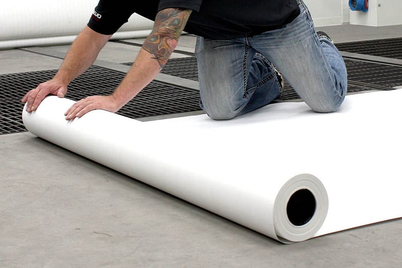 Rolling out GFS Paint Booth Floor protection paper on paint booth floor