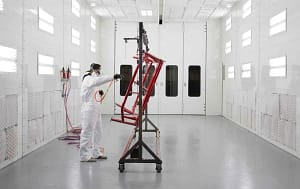 A person painting a frame on a rotisserie inside a GFS Side Downdraft paint booth